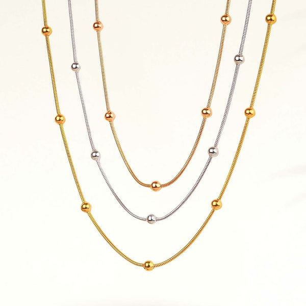 Two gold necklaces with small beads on a white background
