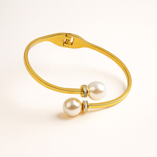 Gold bracelet with two pearls on a light beige background